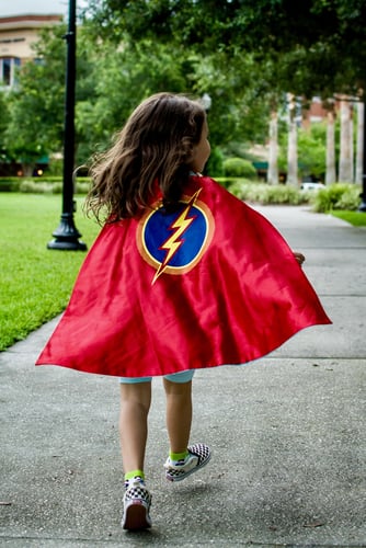 Girl running confidently outdoors wearing a cape