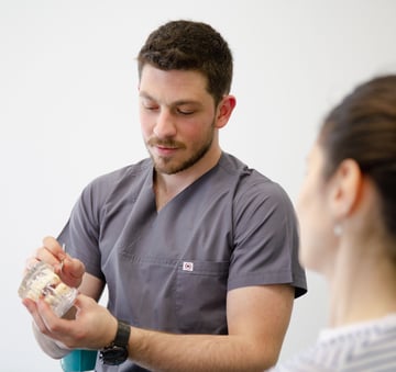 Dr. Roney de Paula mostrando o mockup de um implante dentário ao paciente